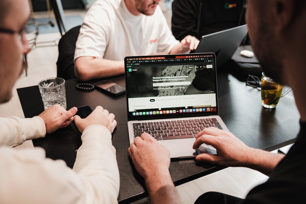 Group of colleagues collaborating on laptops at a modern office table.
